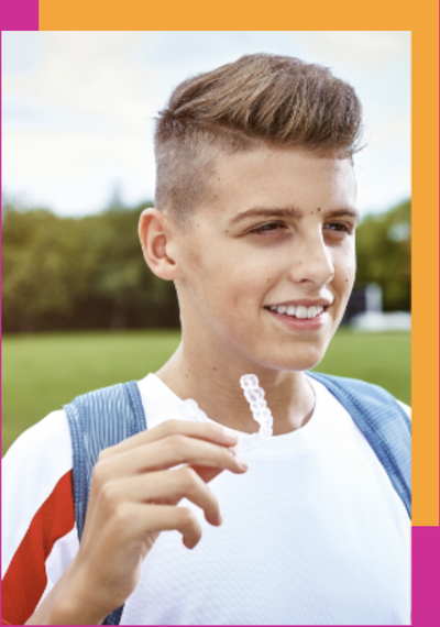 Teen holding Invisalign clear aligners
