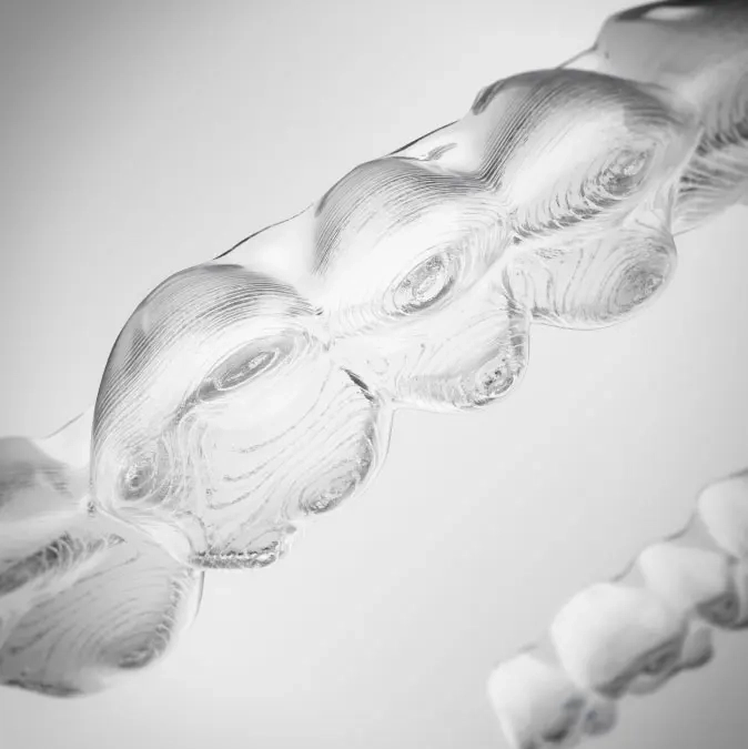 Przykładowe nakładki Invisalign® na szarym gradientowym tle