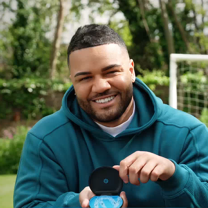 Young man smiling and showing his Invisalign® clear aligners in their case