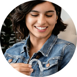 Girl smiling and holding her Invisalign® clear aligner