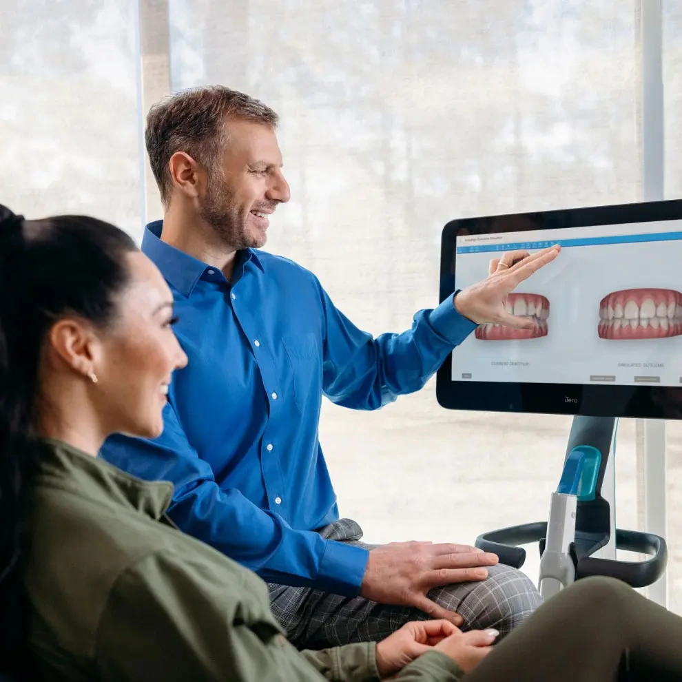 Doctor showing his female patient her potential smile on iTero™ scanner