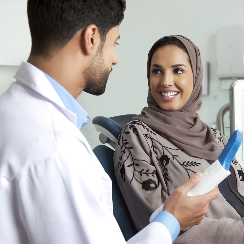 امرأة تبتسم عند طبيب الأسنان أثناء استشارة Invisalign®