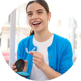 Woman in blue sweater holding aligners and case