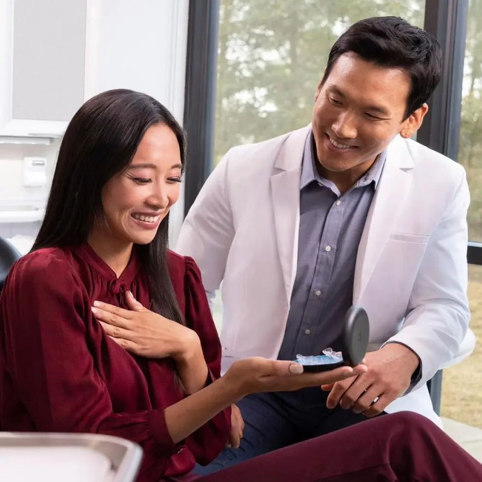 Young woman receives her aligners from a male doctor