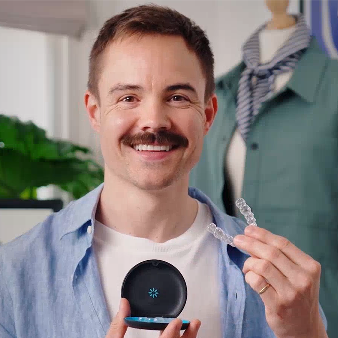 Man smiling and showing his Invisalign® clear aligners in their case