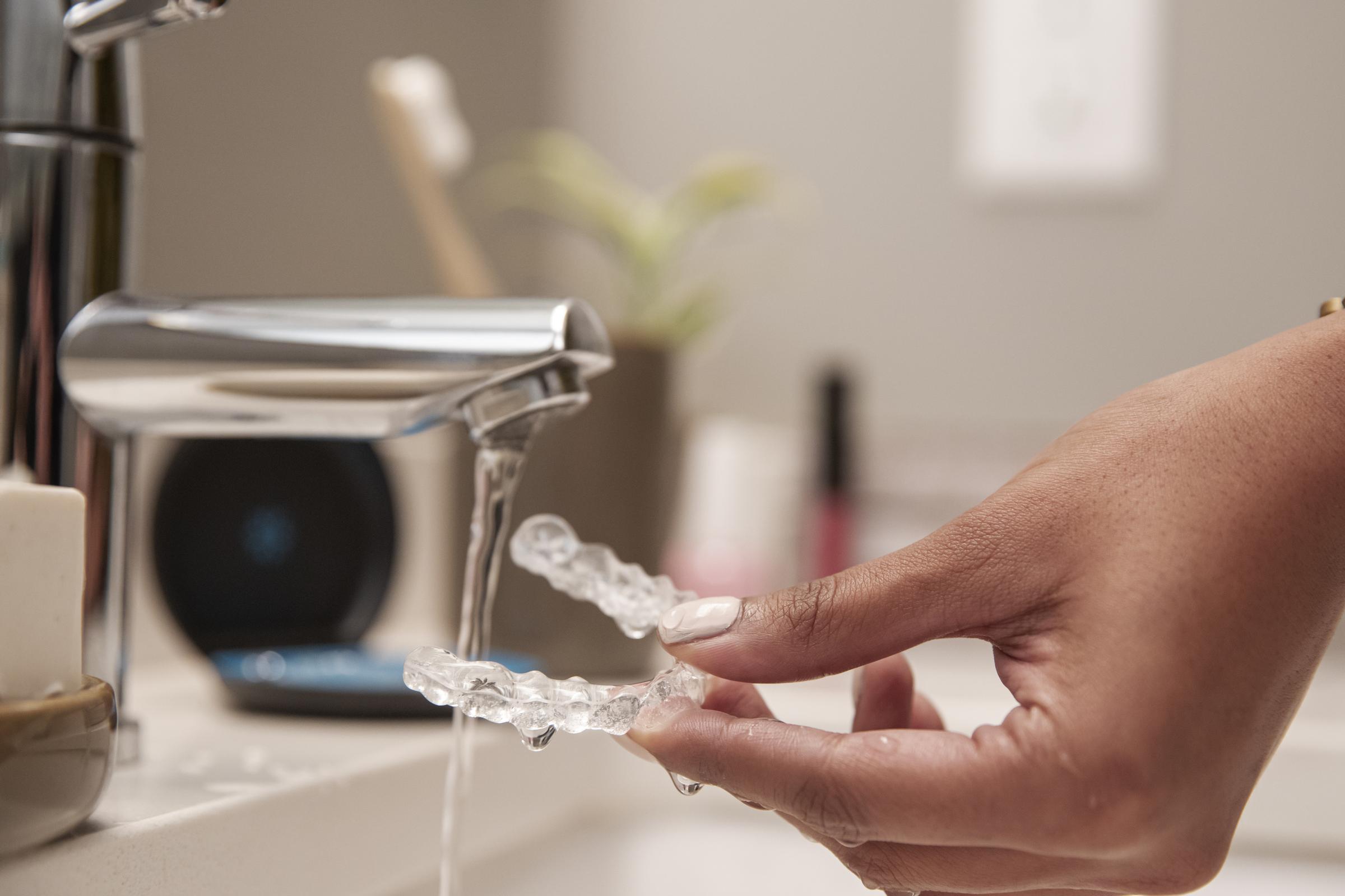 Shot of a hand holding aligners while washing them