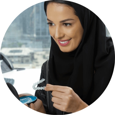 امرأة تحمل تقويم Invisalign® الشفاف وتبتسم
