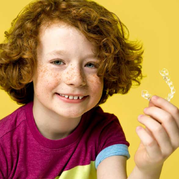 Child holding Invisalign clear aligners