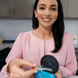 Bir kadın Invisalign şeffaf plak kutusunu tutuyor ve gülümsüyor