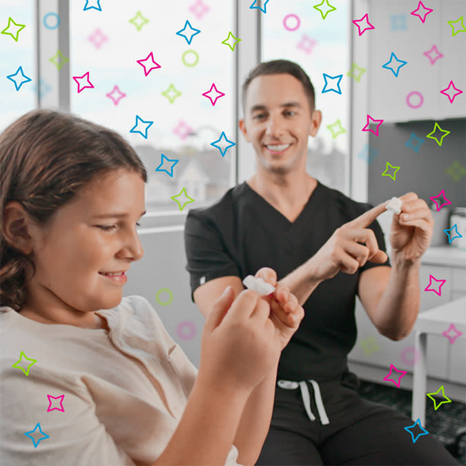 طبيب يعلّم طفلاً كيفية استخدام موسع الحنك من Invisalign® أثناء الاستشارة
