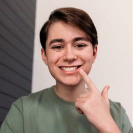 Bir erkek çocuk Invisalign® tedavisinden sonra dişlerini işaret ediyor