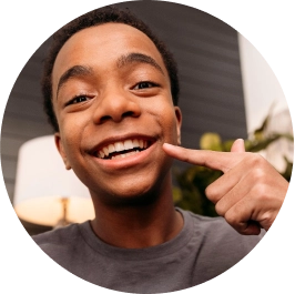 Boy pointing at his teeth after Invisalign® treatment