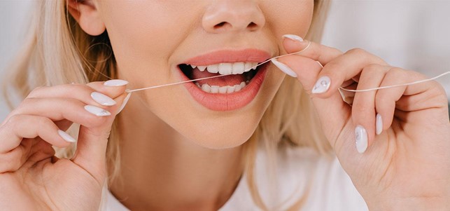 Blonde woman using dental floss