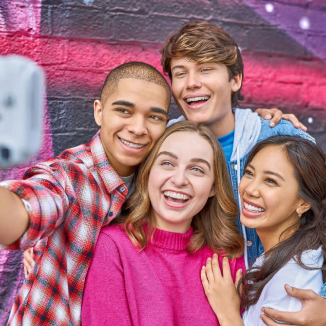 A group of friends smiling after their  Invisalign® treatment