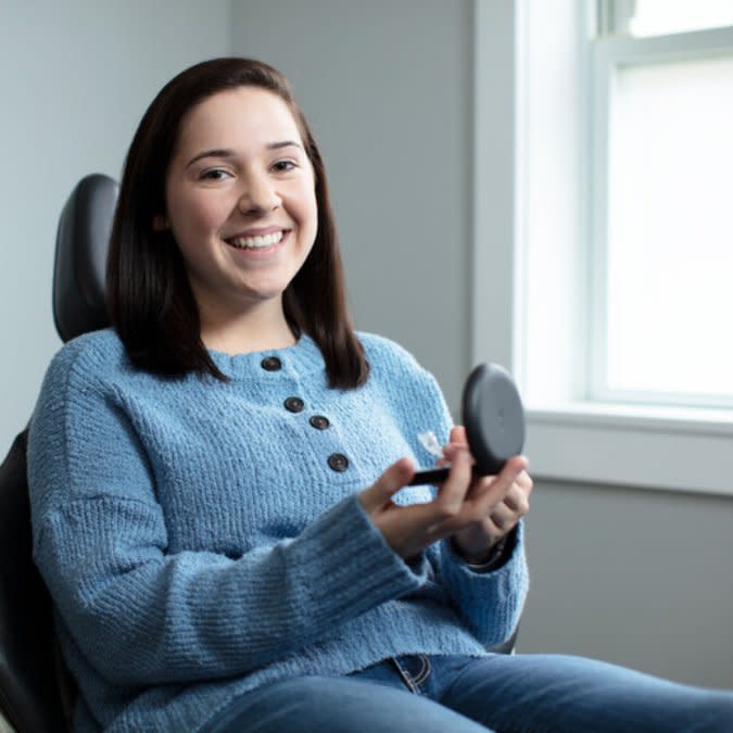 Genç bir kadın Invisalign şeffaf plaklarını kutusunda tutuyor