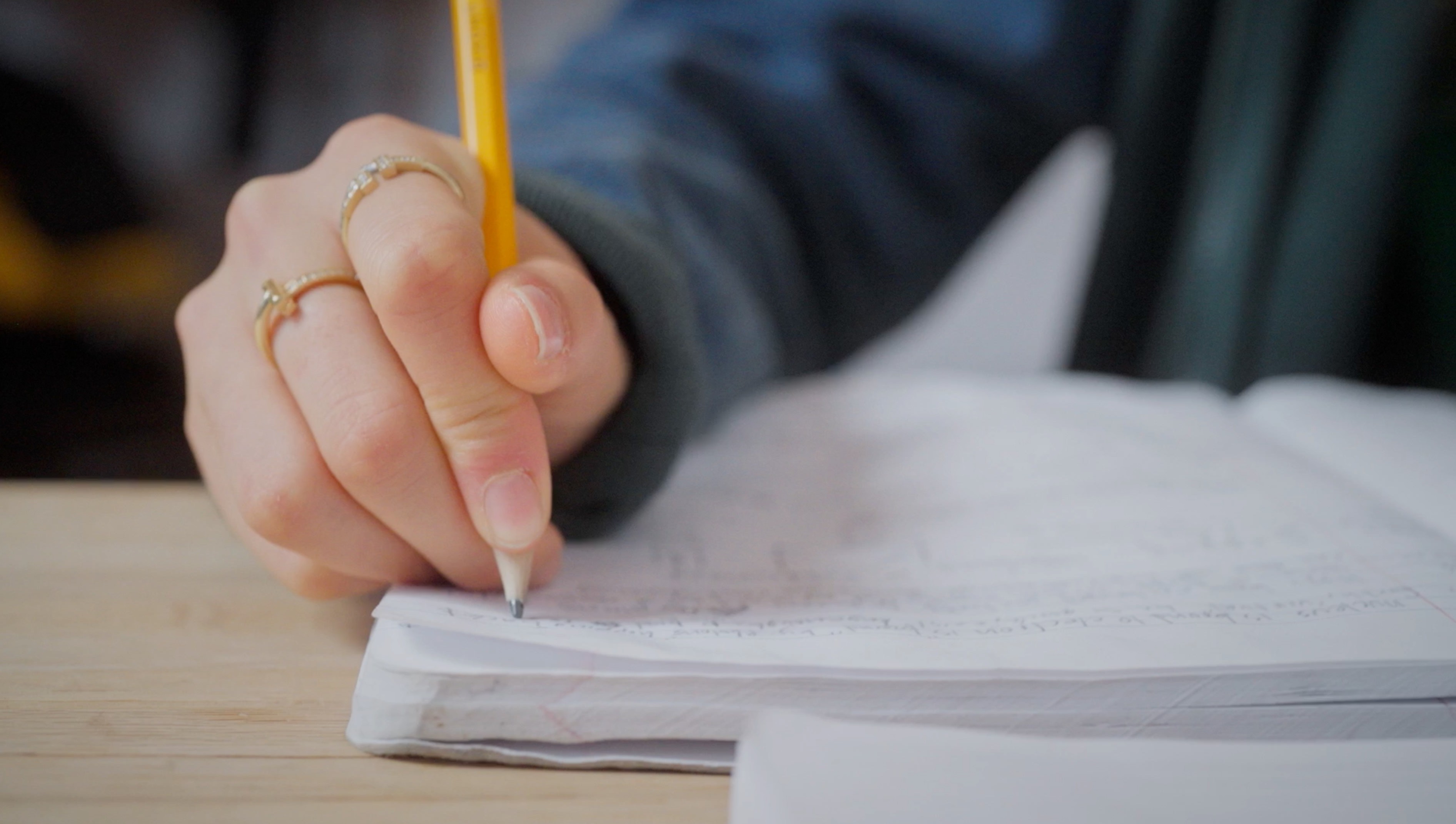 Close-up of hand writing notes in a notebook with pencil, Eileen Gu X Games training and preparation journal