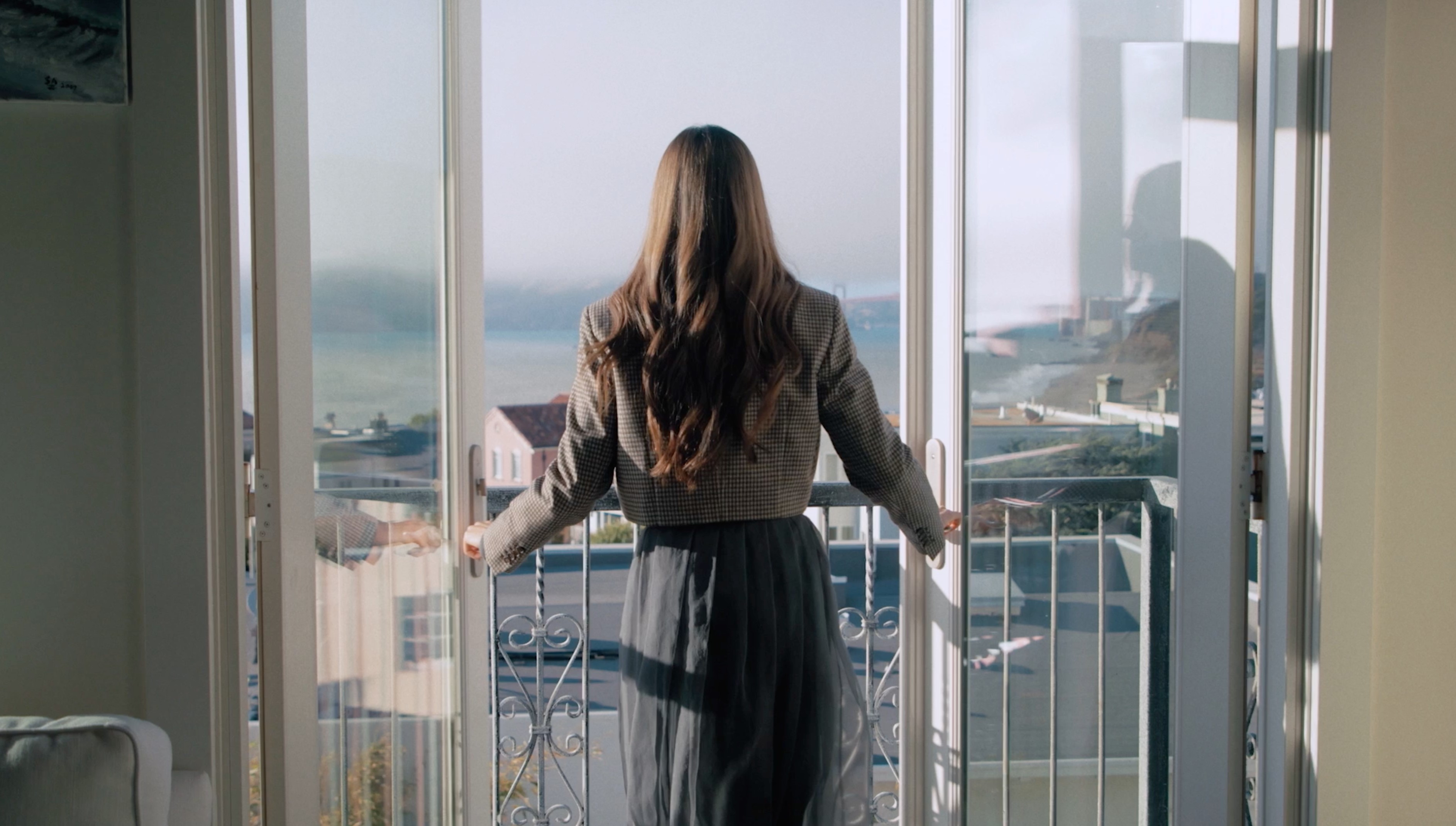 Eileen Gu opening balcony doors to a coastal ocean view, X Games athlete lifestyle photography