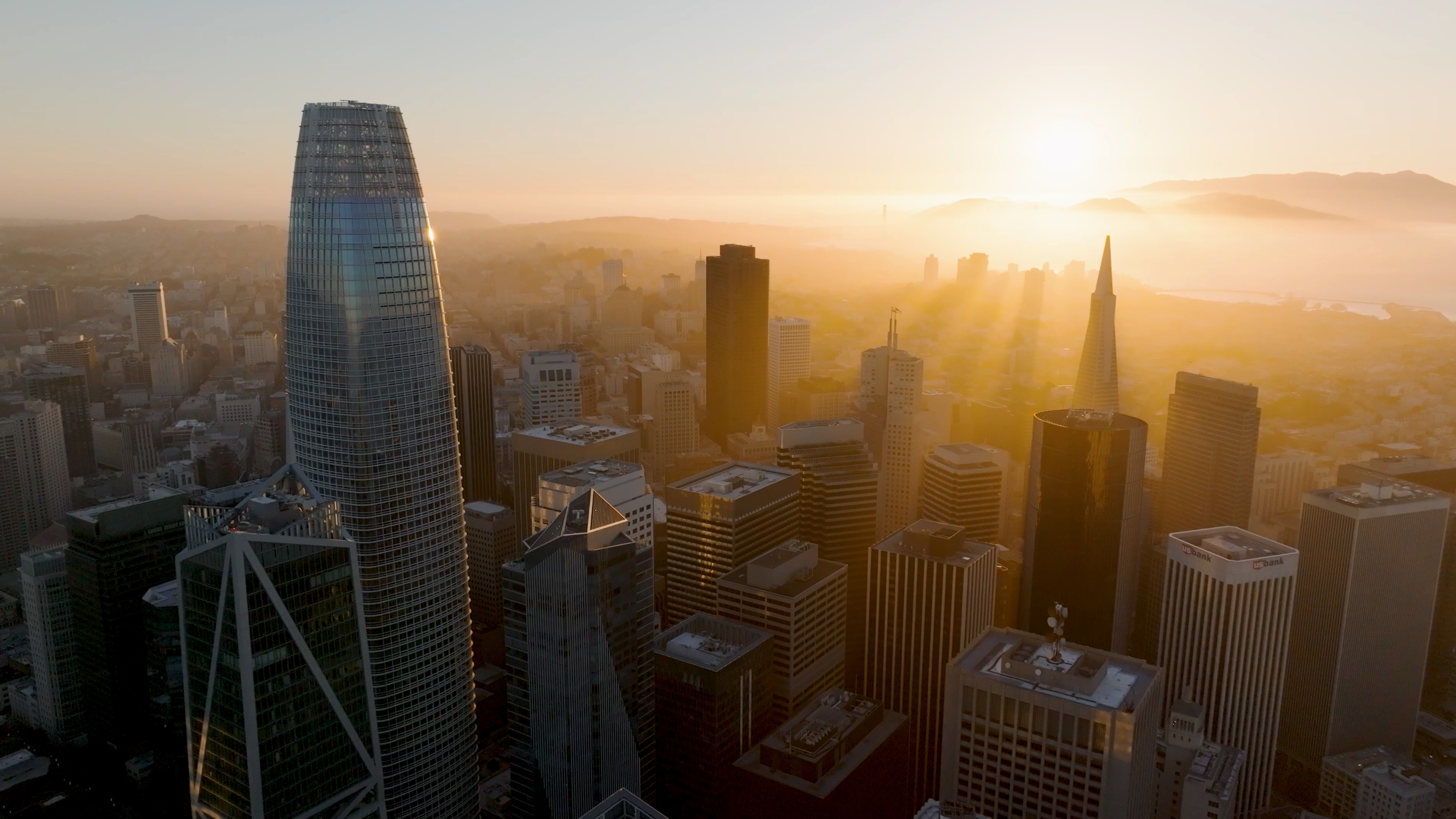 Aerial drone shot of the San Francisco skyline at golden hour featuring Salesforce Tower and the Transamerica Pyramid. Shot for Philip Farr's luxury real estate brand video by The Bureau.