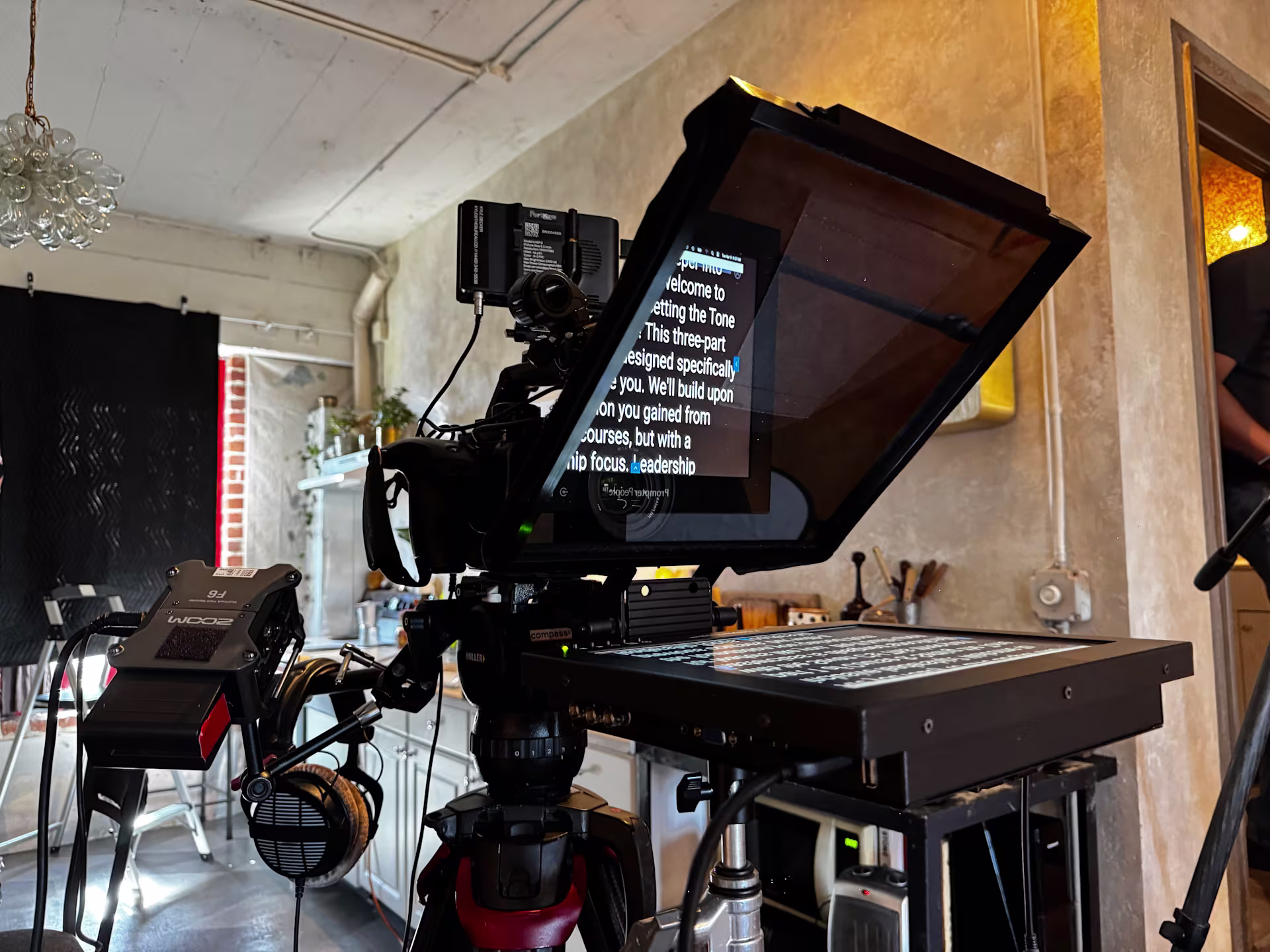 A professional teleprompter and beam-splitter rig mounted on a cinema camera during a corporate video shoot, with a script reflected on the glass — illustrating the modern teleprompter workflow used in executive interviews.