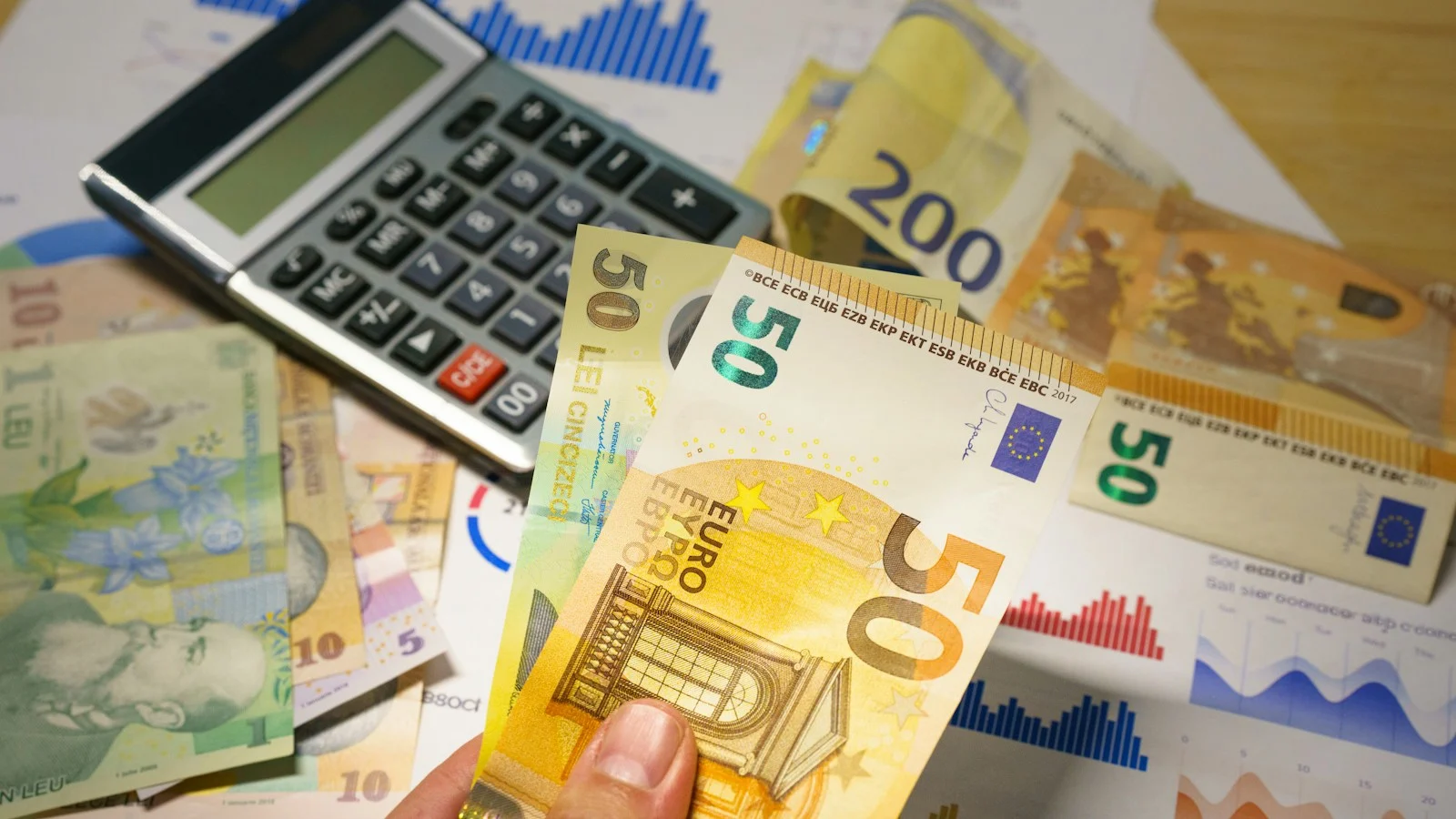 Currency hedging for importers: reviewing foreign-currency banknotes and calculations; Jakub Żerdzicki / Unsplash. Illustrative currency and budget planning.
