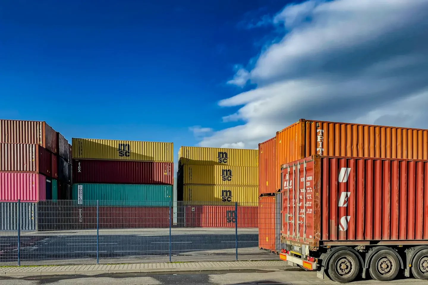 Truck beside stacked shipping containers