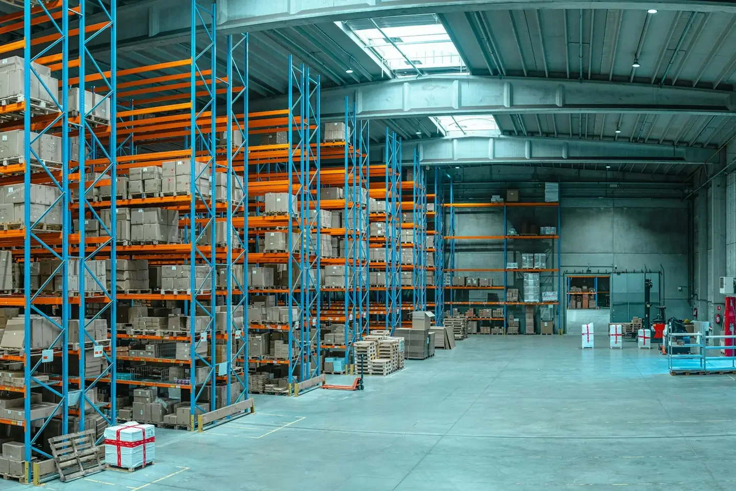 Tall blue metal shelving units filled with cardboard boxes in a large warehouse
