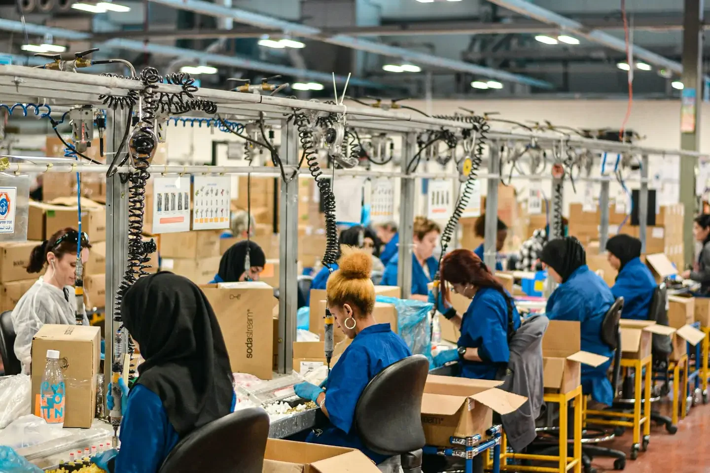People in blue uniforms working at an assembly line in a large factory