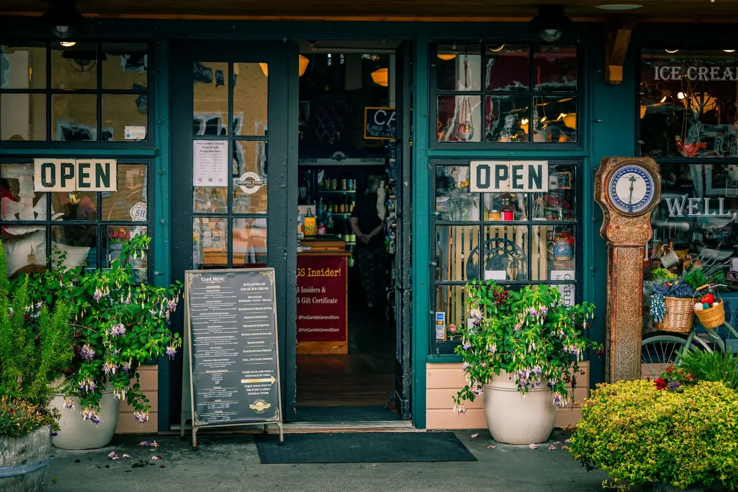 Green storefront with open signs and plants