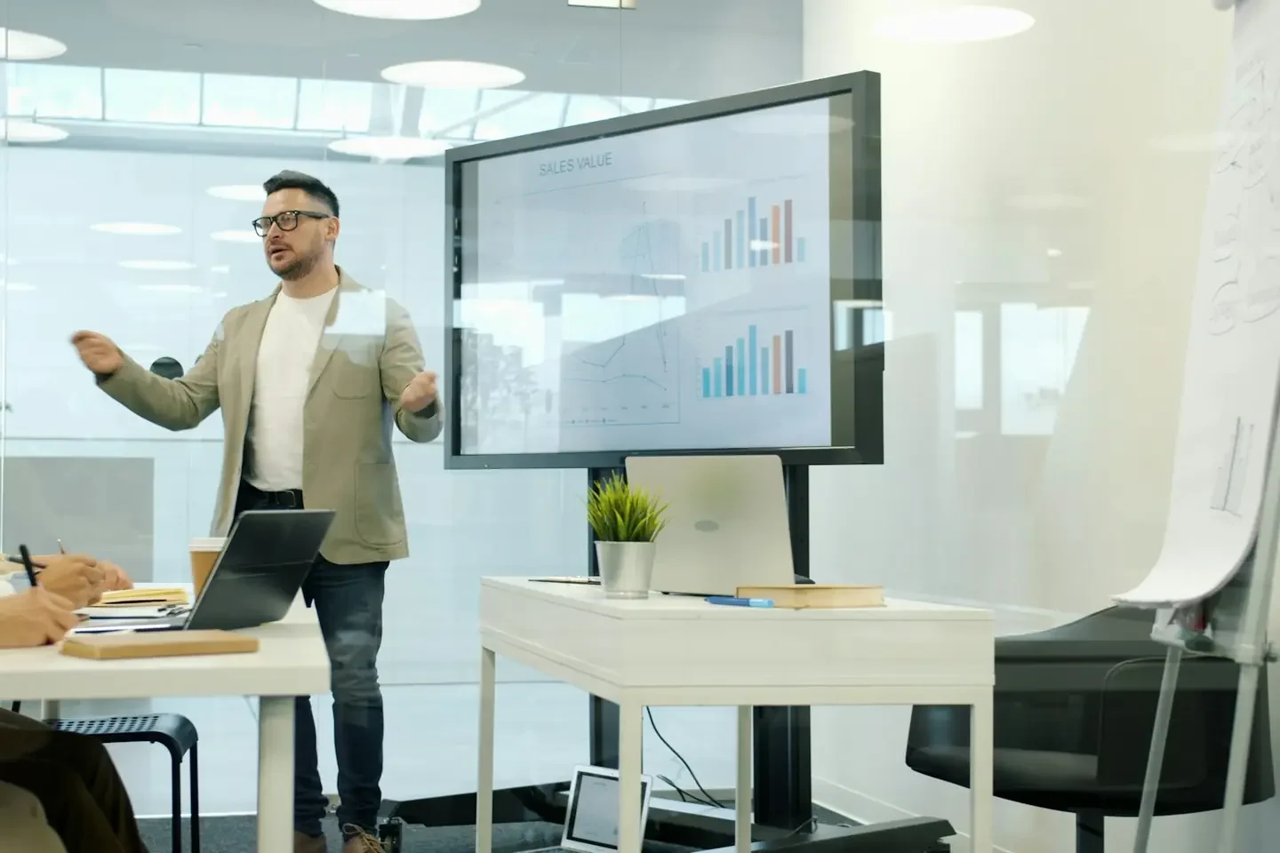 Man presenting data on a large screen to colleagues