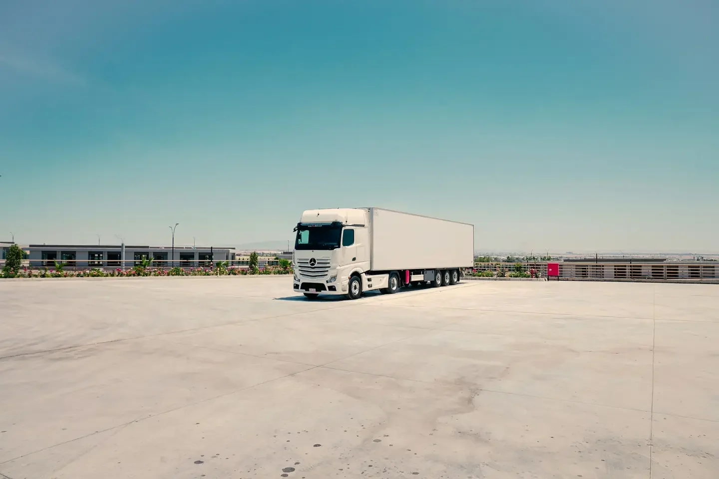 A white semi-truck and trailer parked in an empty lot