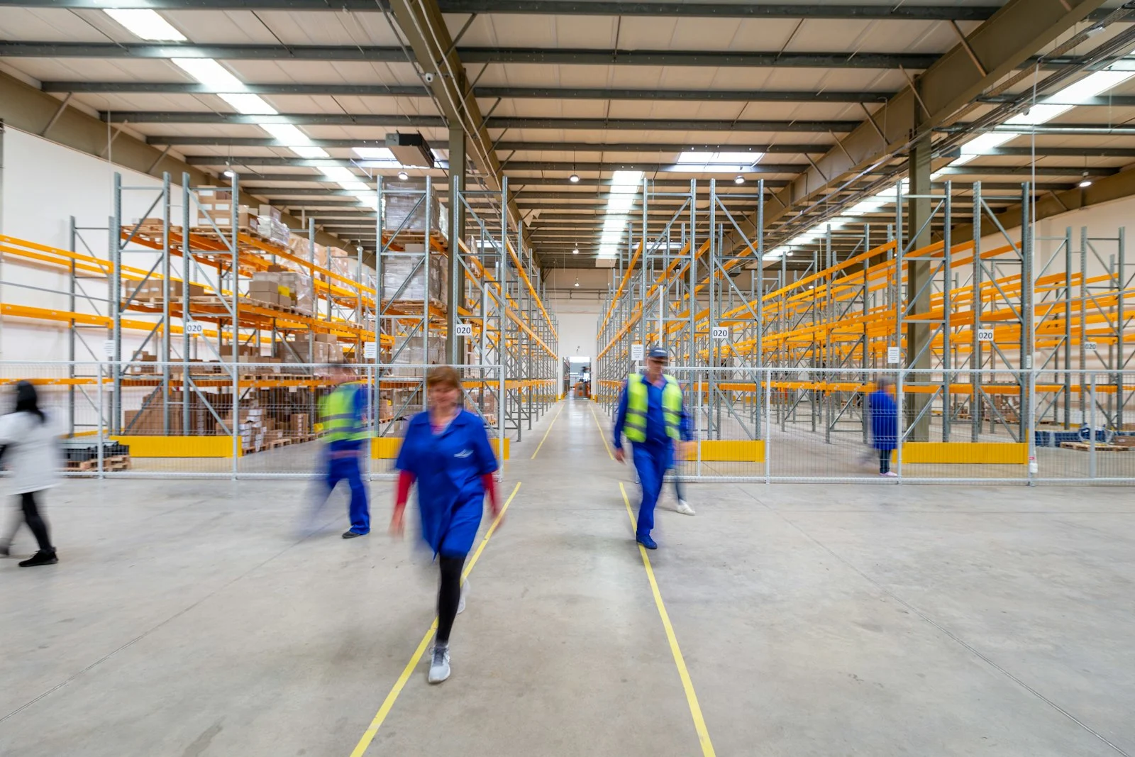 Workers walking through a distribution warehouse aisle. Photo via Unsplash (c_4eaGRDSVU).
