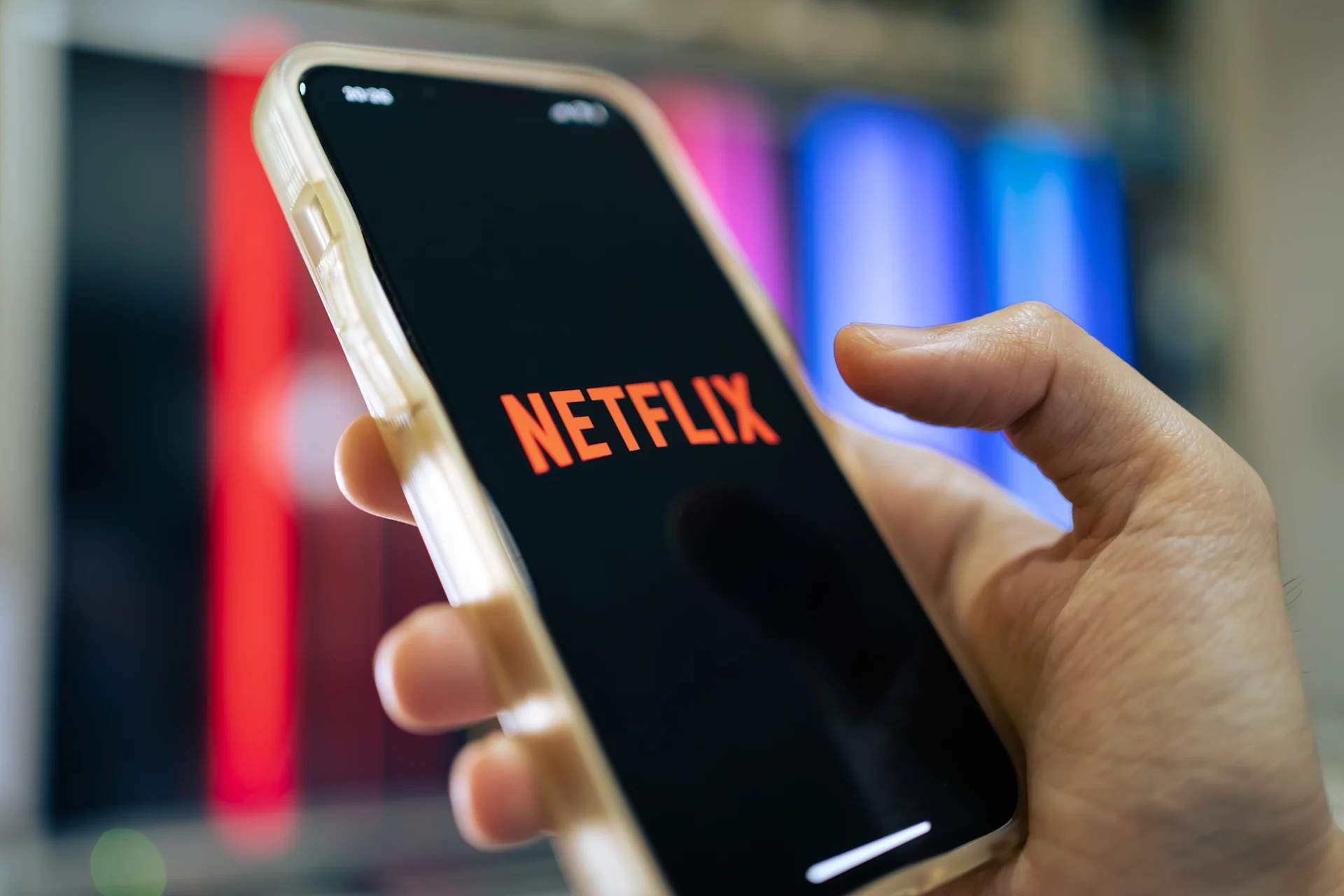 Man holding a phone while the Netflix app launches