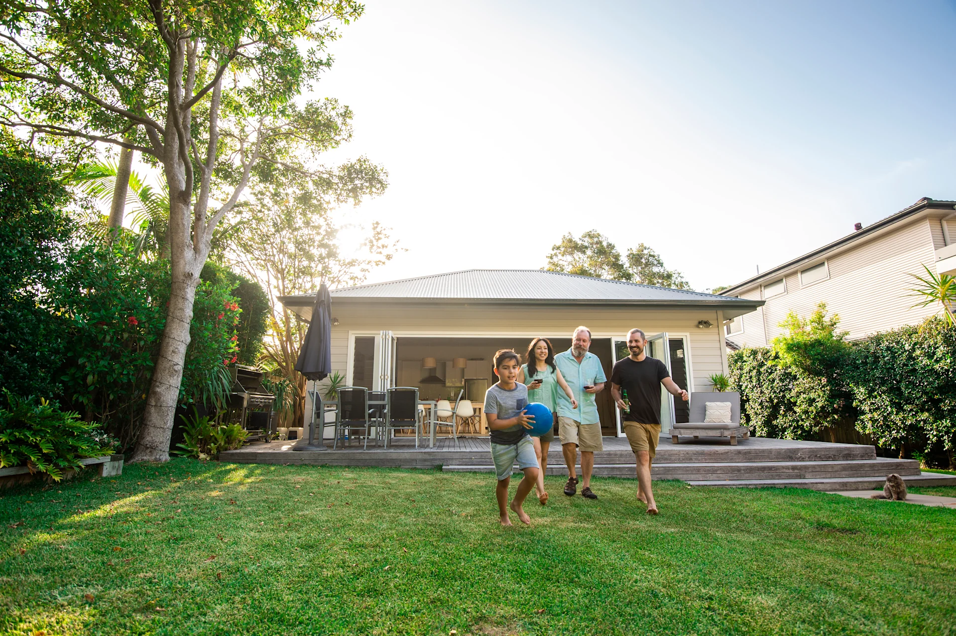 A family of four walks together in a green yard, enjoying a sunny day.