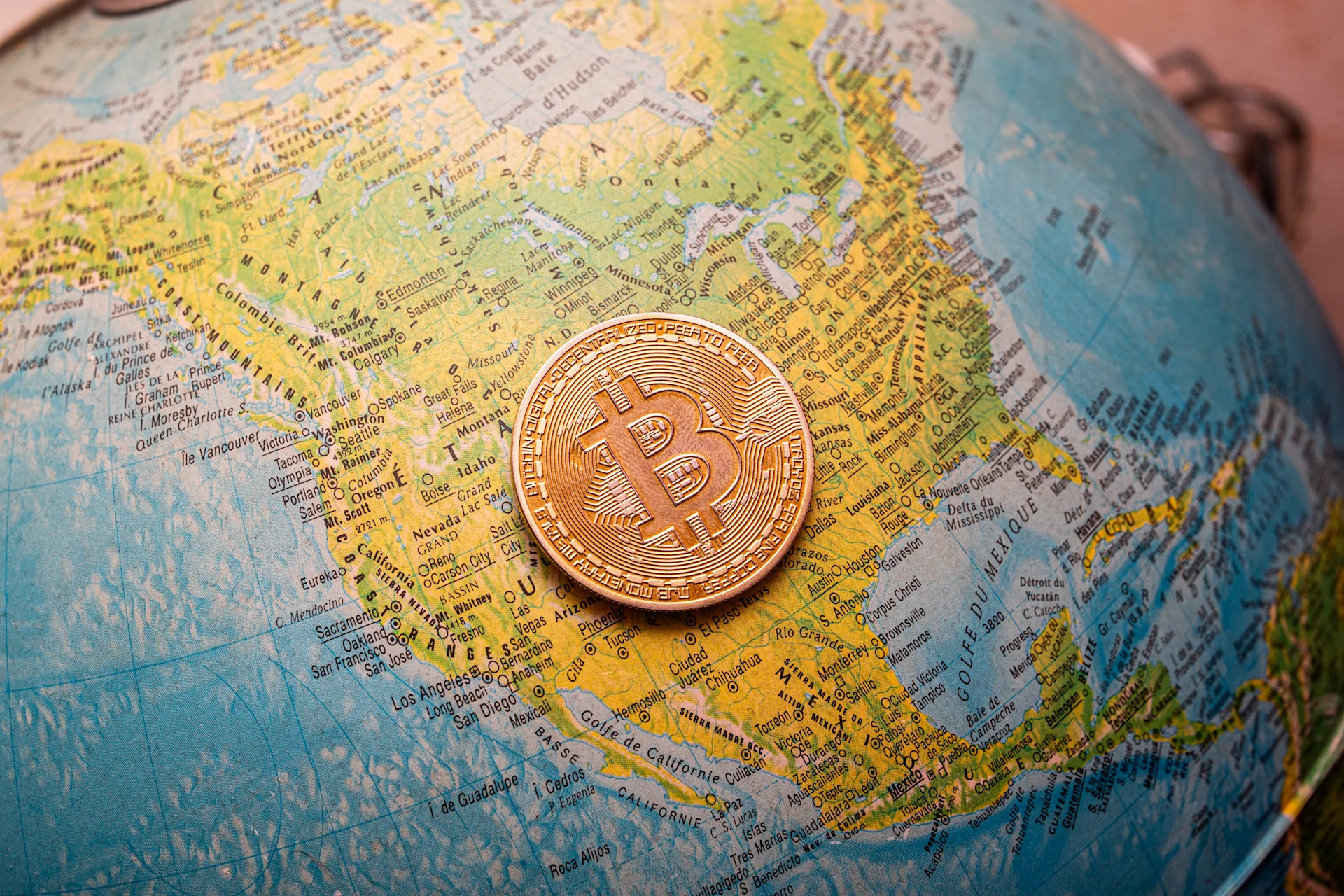 Bitcoin symbol overlaying a world map, illustrating global cryptocurrency presence and influence.