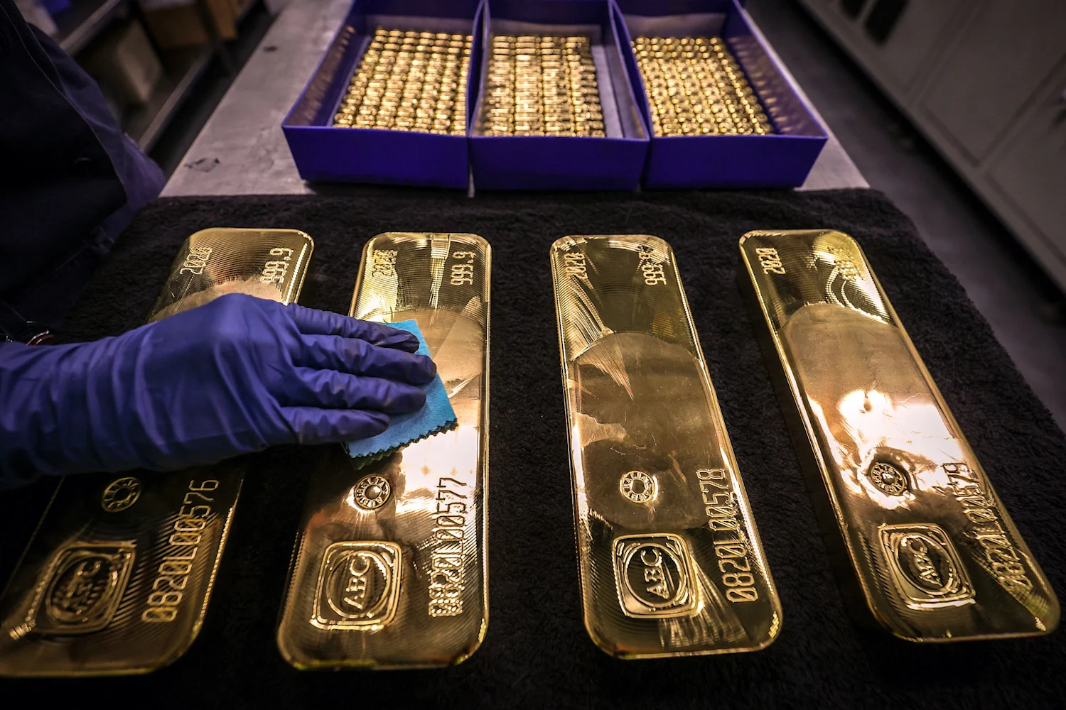 A worker meticulously cleans gold bars, highlighting their luster and preparing them for display.