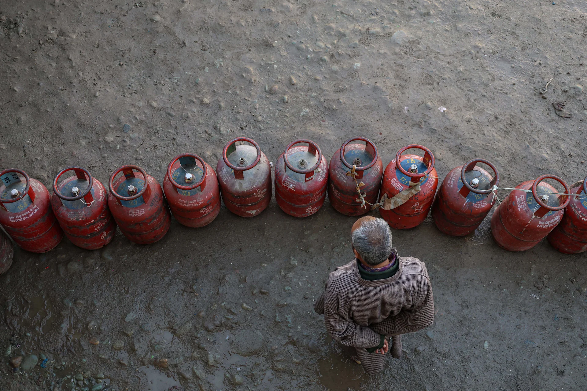 A man stands near the empty liquefied petroleum gas (LPG) cylinders outside a gas agency amid supply disruptions following the U.S.-Israeli conflict with Iran