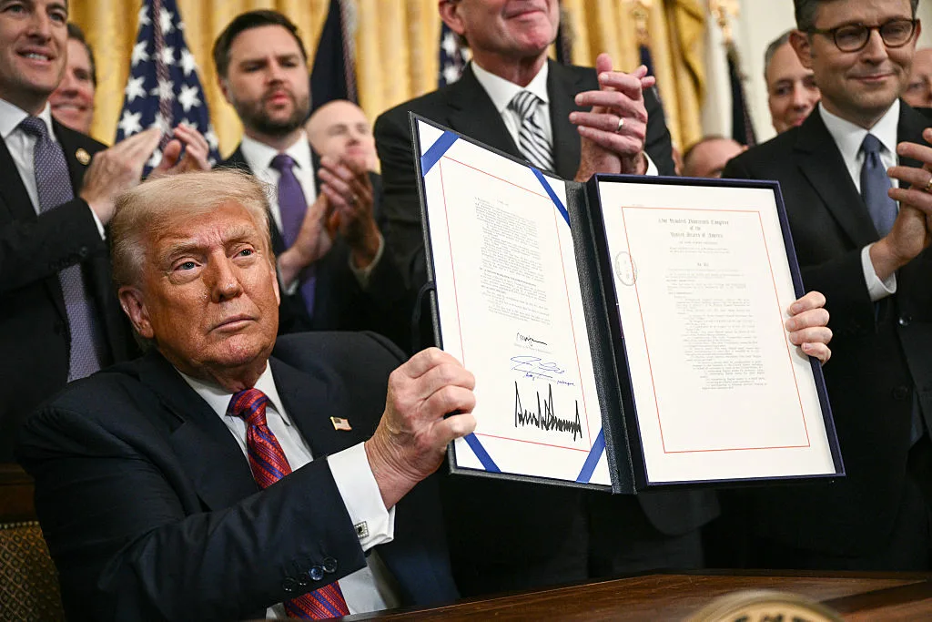 US President Donald Trump displays the GENIUS Act after signing it in the East Room of the White House in Washington