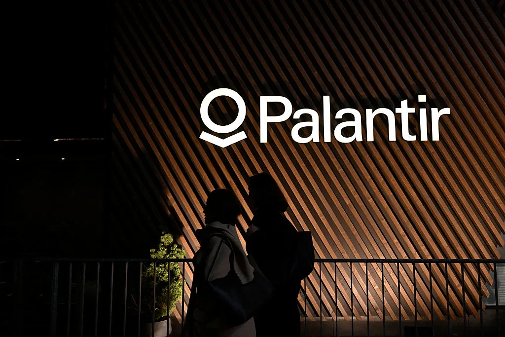 Pedestrians walk past the Palantir's booth during the World Economic Forum