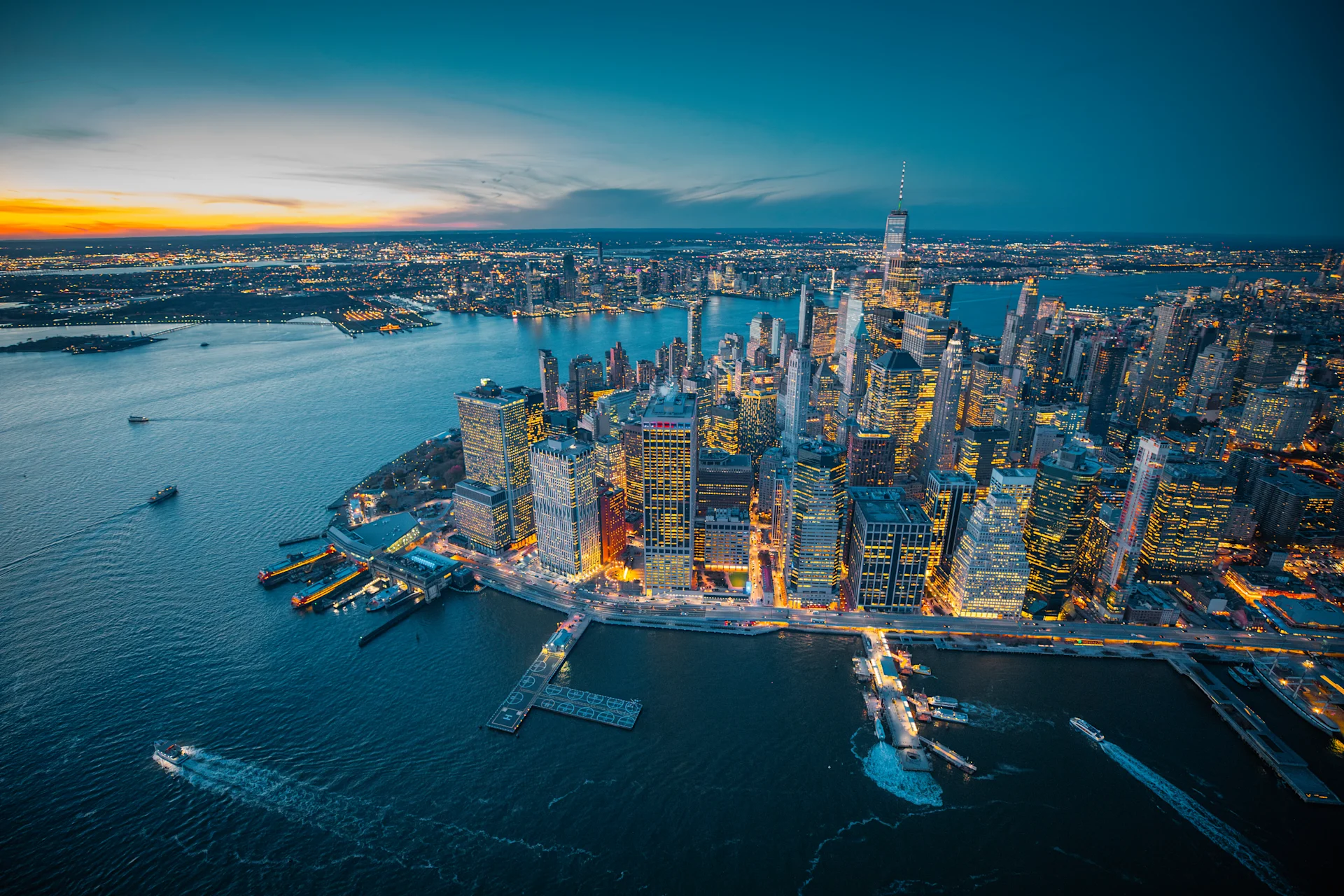 Elevated perspective of the city skyline at dusk, featuring twinkling lights and a fading sunset backdrop.