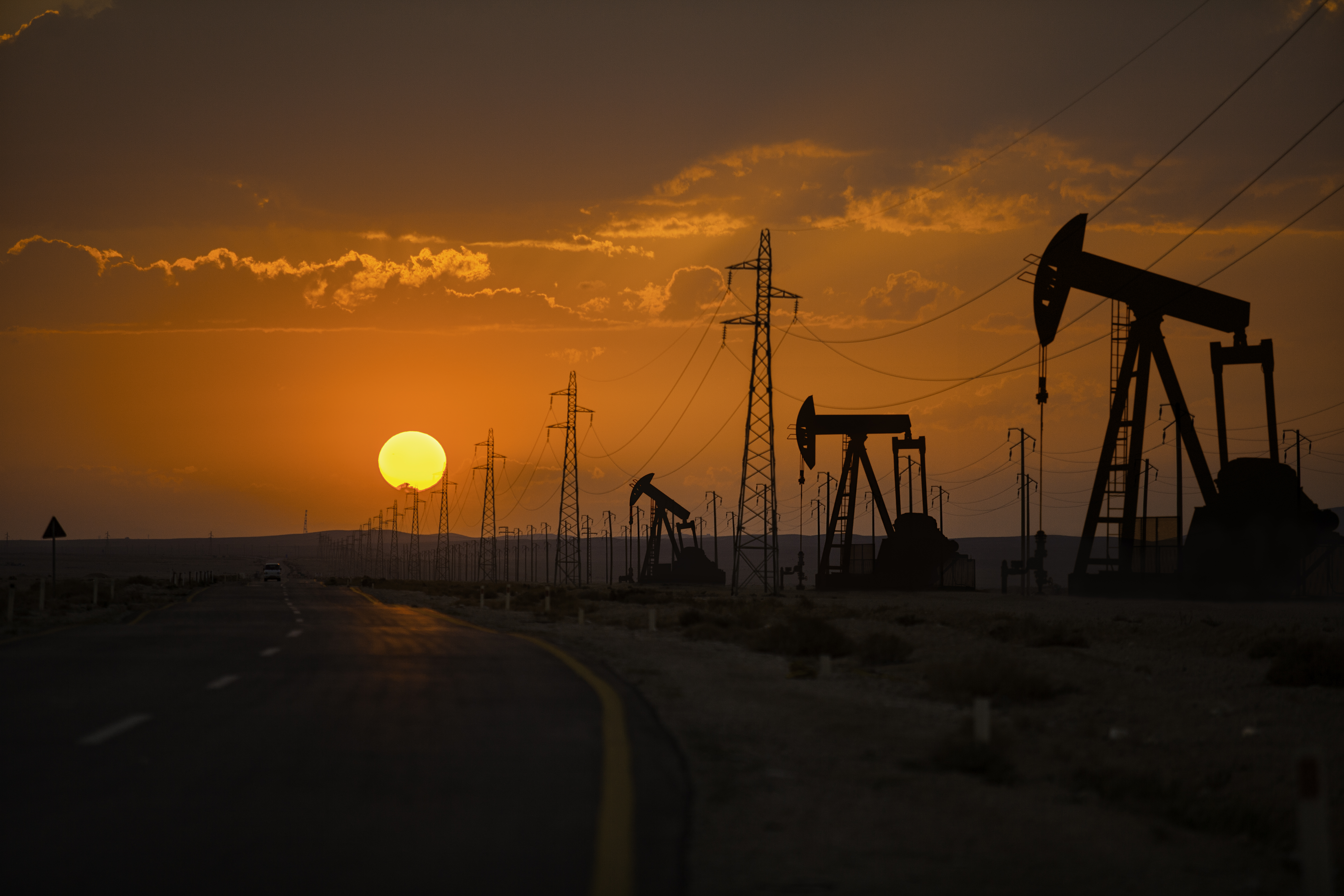 Oil wells and power lines on the side of the highway