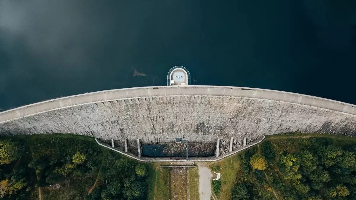 overhead view of a dam on a lake, illustrating the harmonious blend of human engineering and natural scenery.