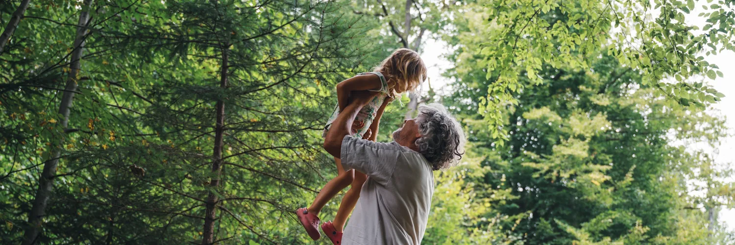 Father and daughter playing in an area filled with trees