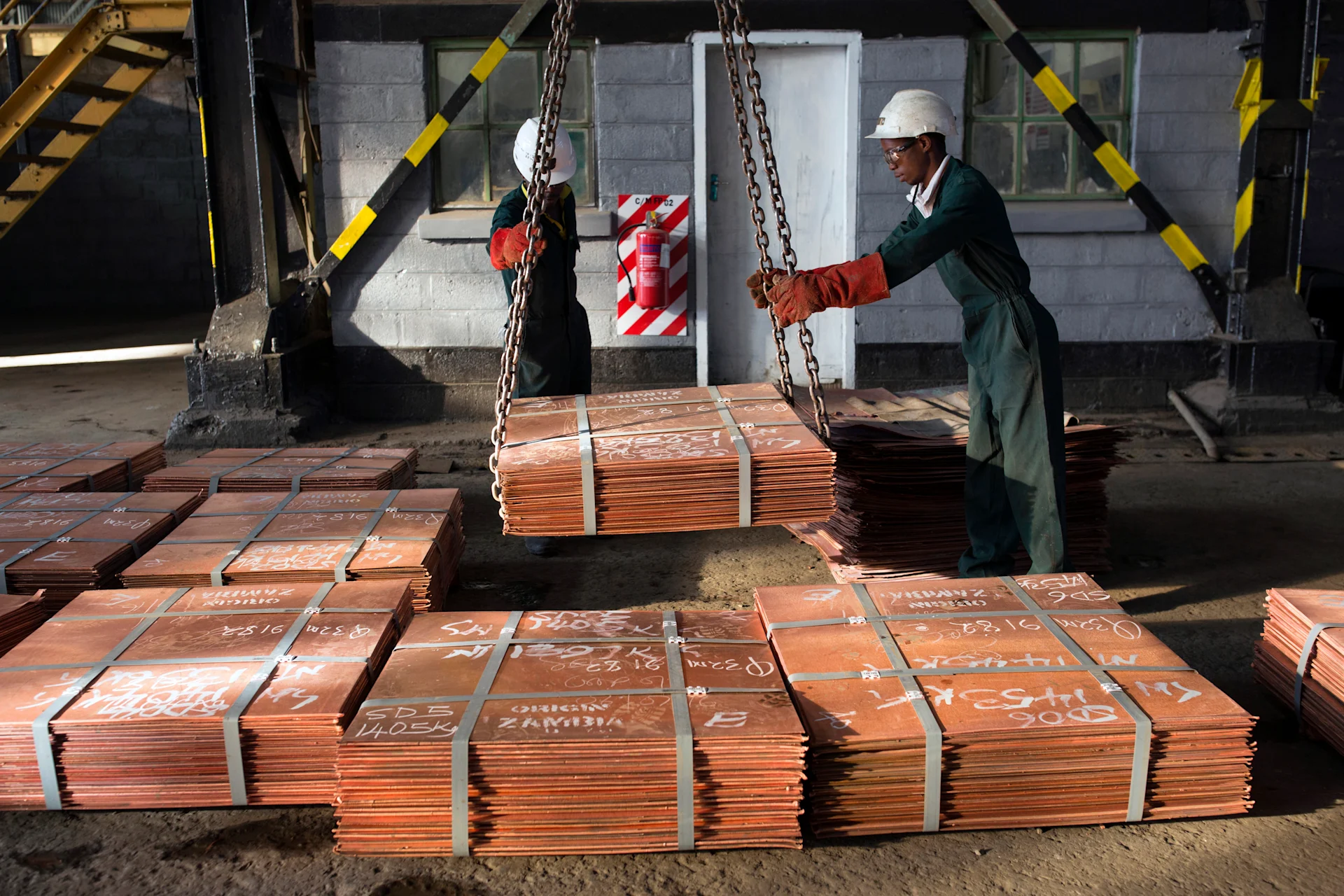 Workers move batches of copper sheets