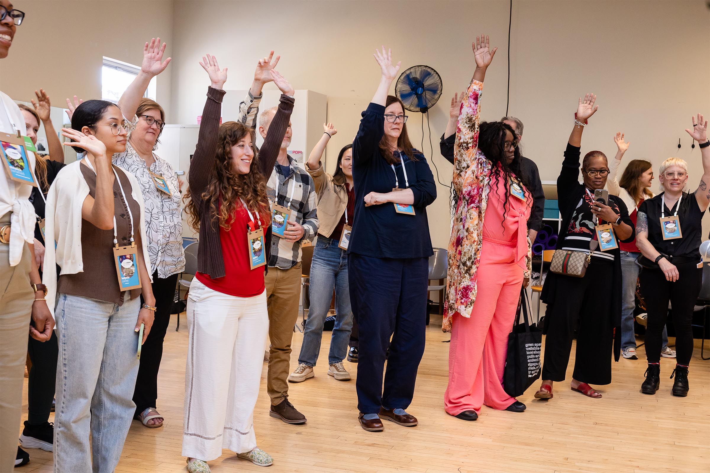The Vision is Yours 2026 by Side A Photography. Smiling participants raise hands during workshop about engagement and facilitation techniques.