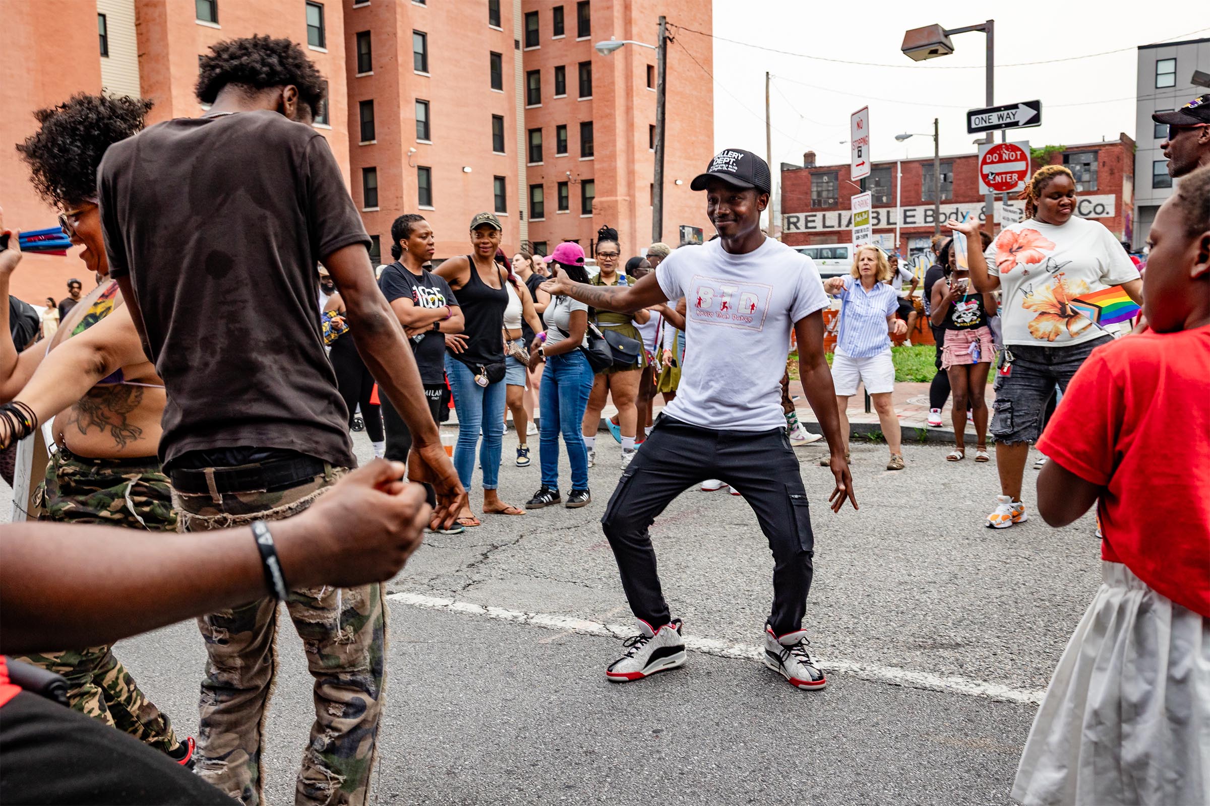 Attendees of Baltimore Pride Promenade 2025 dance joyfully on Charles Street during after party and unveiling of Inviting Light installations by Phaan Hwong and Tony Shore.
