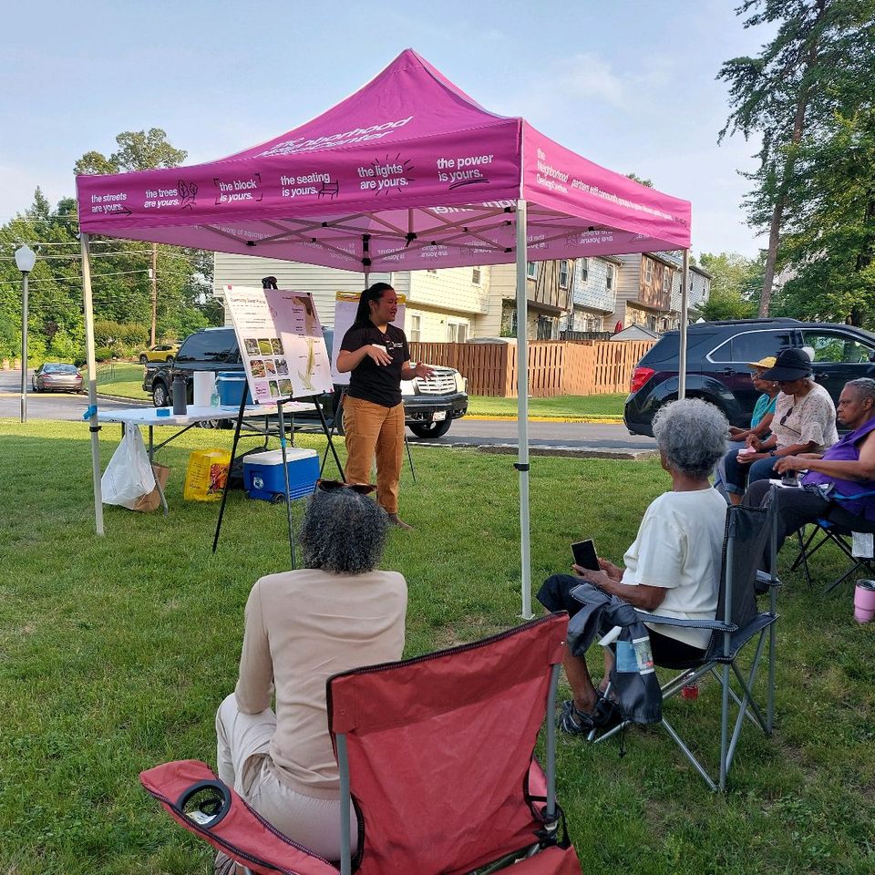 Micaela presents to community outside under NDC tent.