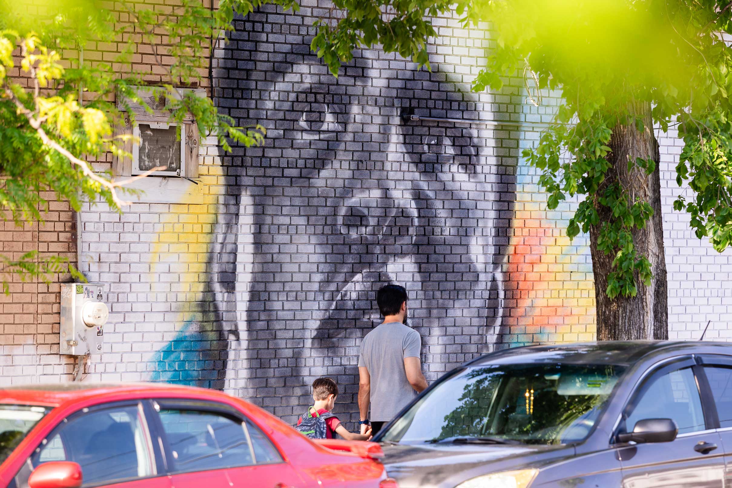 Father and son walk along tree-lined mural in Hyattsville, Maryland.