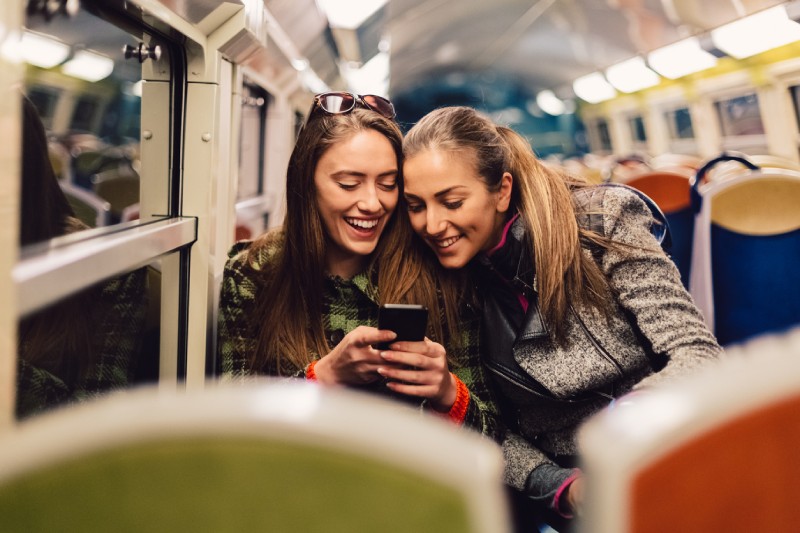 Two women on WhatsApp on a train at night