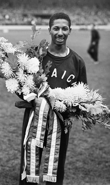 Herb McKenley in a black and white photo holding flowers after olympic win