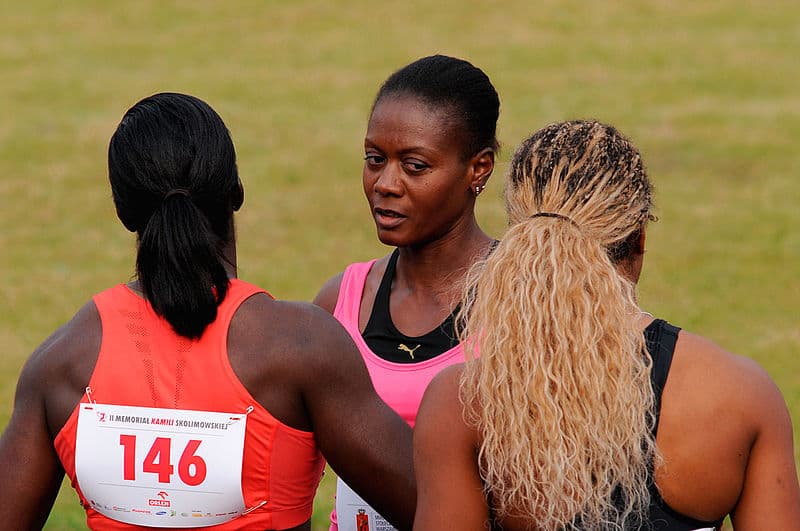 Two women engaged in discussion with Merlene Ottey on a track a field while in competition